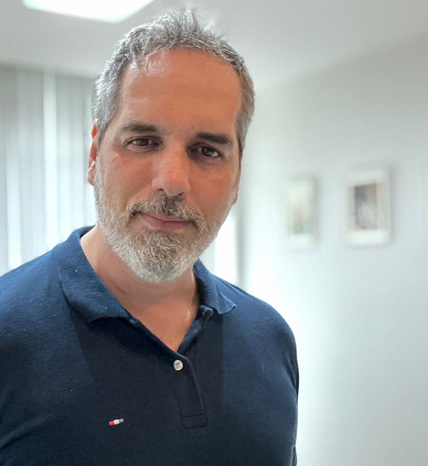 Middle-aged man with salt-and-pepper hair and beard, wearing a navy blue polo shirt.